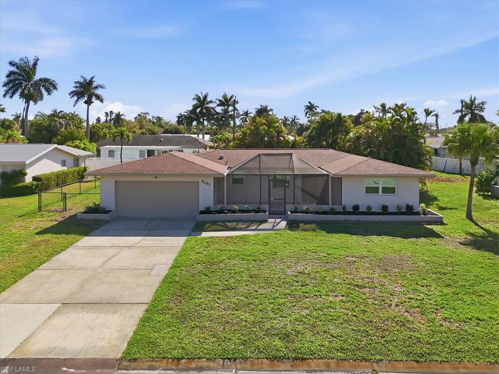 Ranch-style house featuring a front yard, concrete driveway, a garage, glass enclosure, and a shingled roof