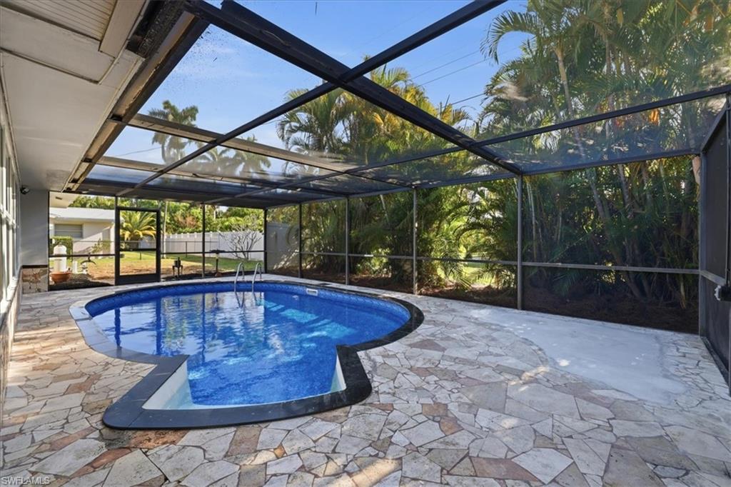 old Outdoor pool featuring a sunroom, glass enclosure, and a patio