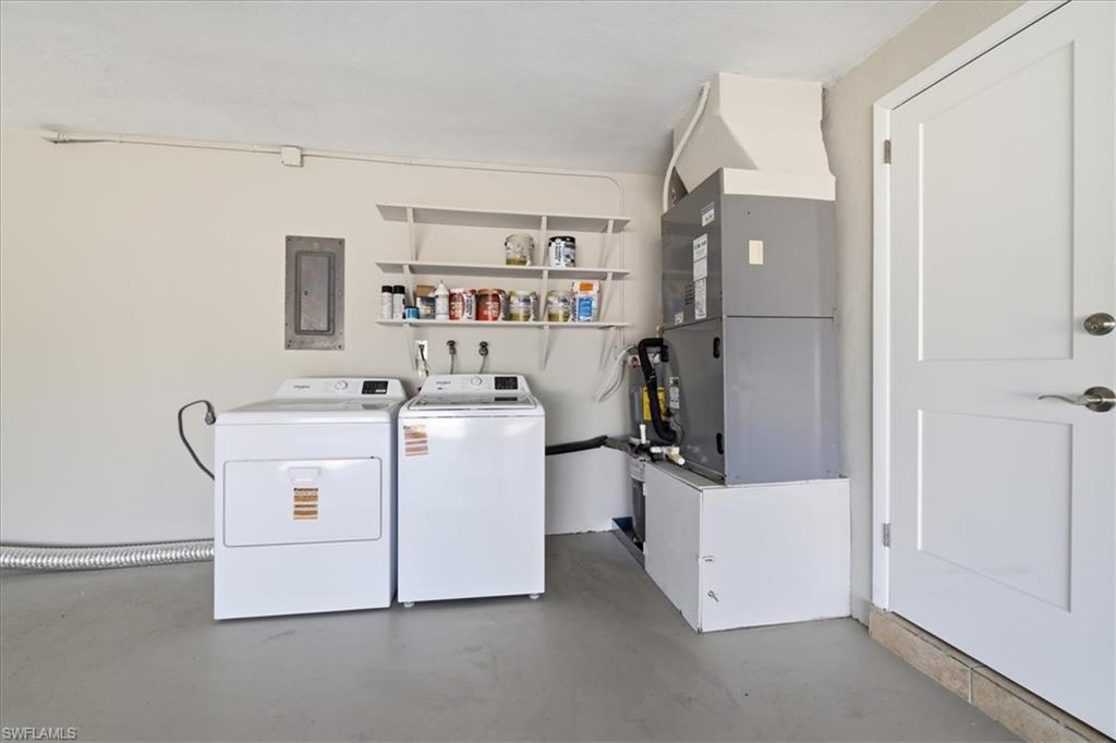 Laundry area with independent washer and dryer, concrete floors, heating unit, and electric panel