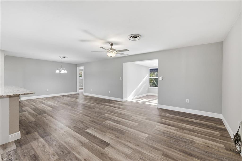 Empty Livingroom with a ceiling fan, dark wood finished floors, and a chandelier