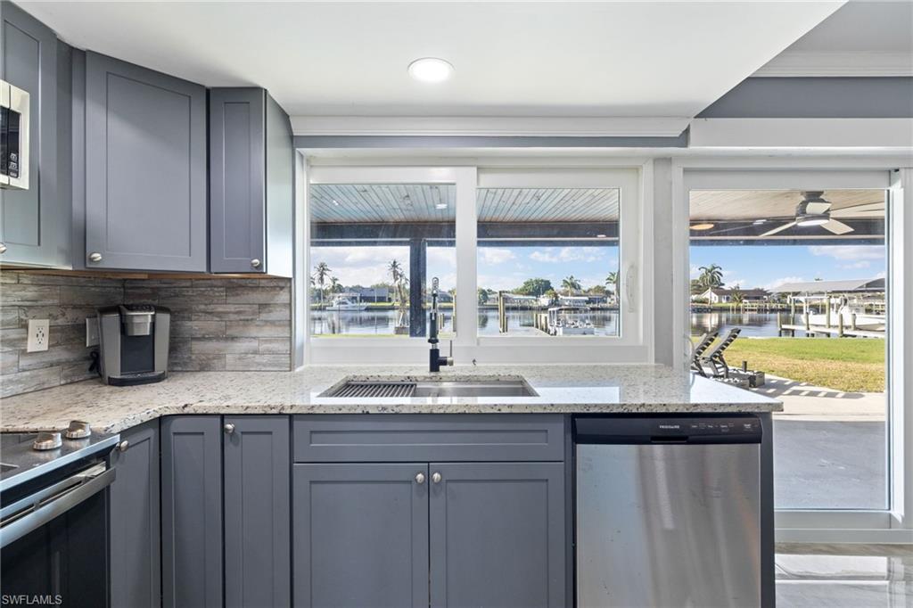 Kitchen featuring stainless steel appliances, gray cabinetry, and light stone counters