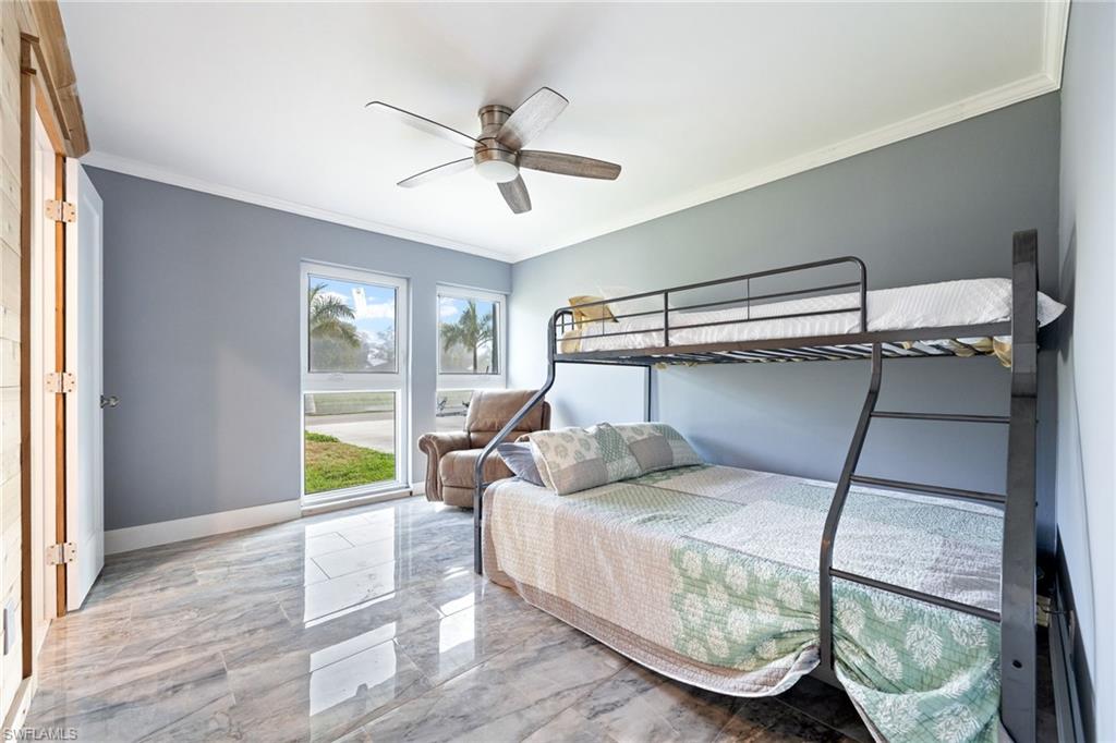 Bedroom featuring ornamental molding, ceiling fan, and light marble finish floors
