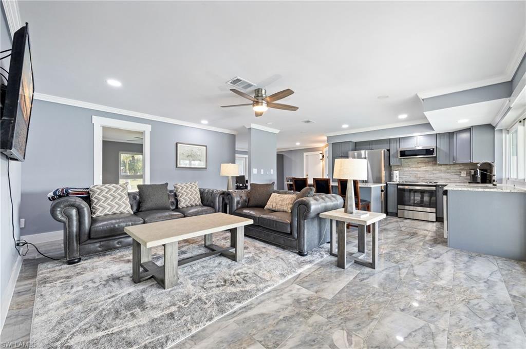 Living room featuring a ceiling fan, crown molding, and recessed lighting