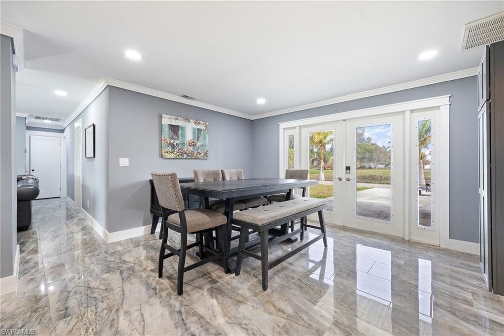 Dining area featuring french doors, ornamental molding, light marble finish floors, and recessed lighting