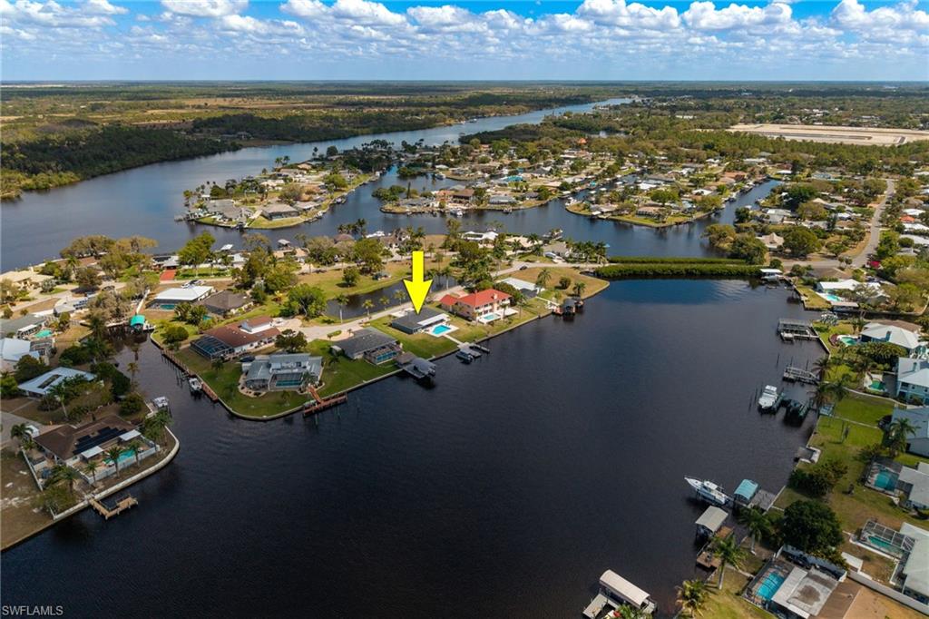 Aerial view of property and surrounding area featuring a nearby body of water and nearby suburban area