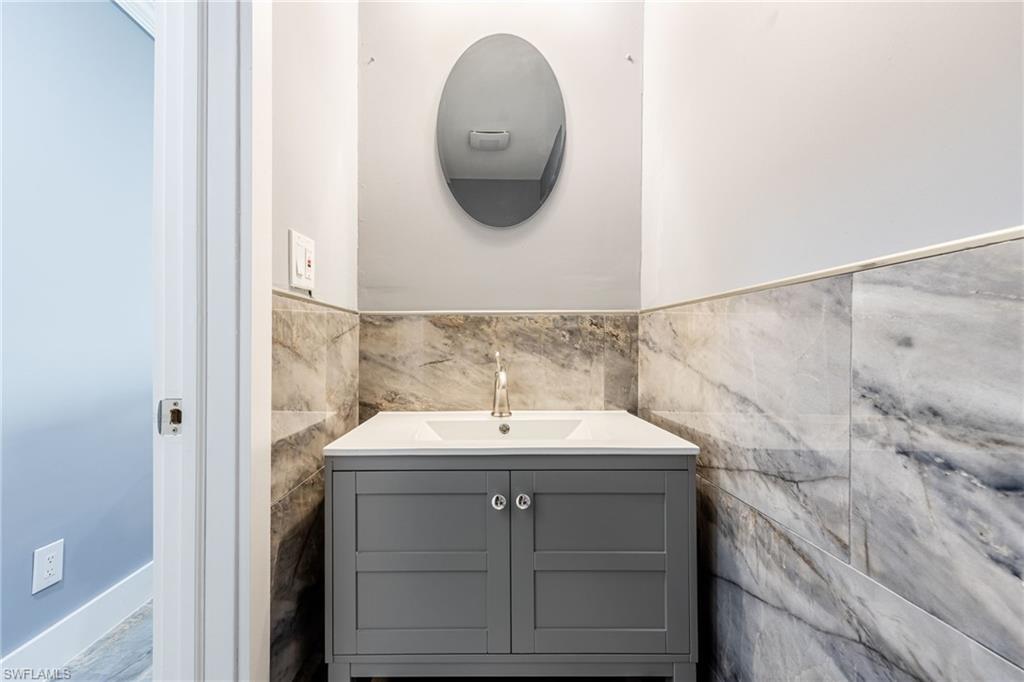 Bathroom featuring vanity, tile walls, and a wainscoted wall