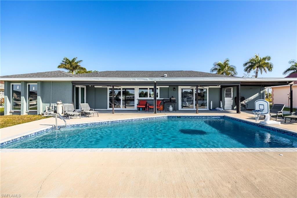 Rear view of house with a patio, an outdoor pool, and roof with shingles