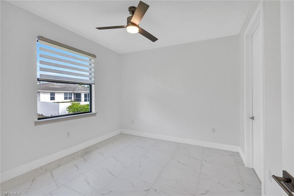 Unfurnished room featuring light marble finish floors and ceiling fan
