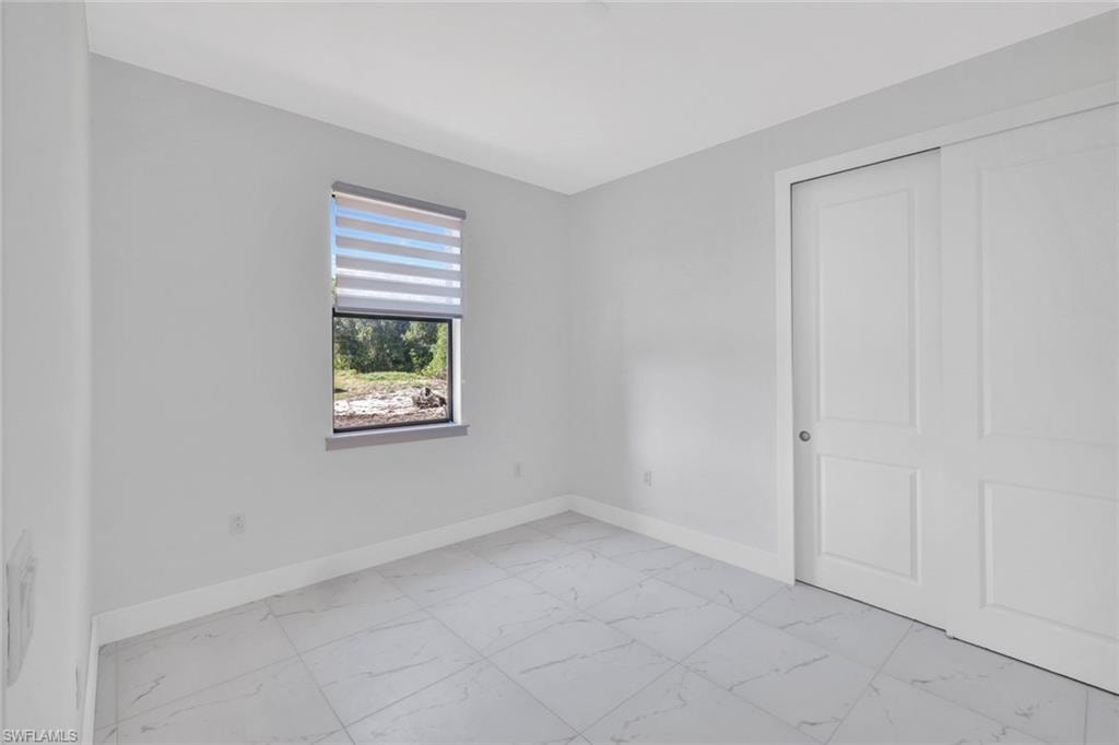 Unfurnished bedroom with light marble finish flooring and a closet