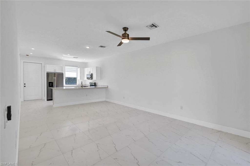 Unfurnished living room featuring light marble finish flooring, a ceiling fan, and recessed lighting