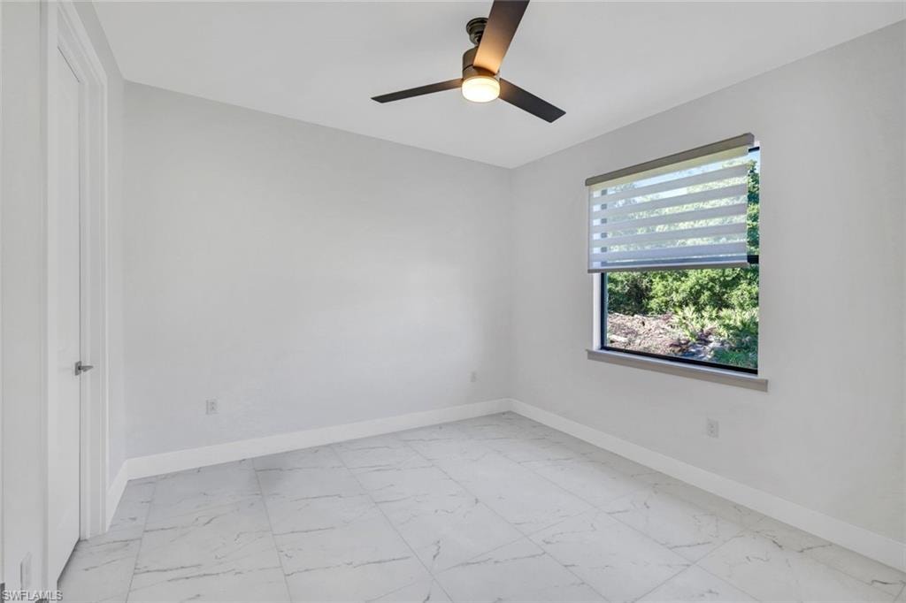 Unfurnished room featuring light marble finish flooring and ceiling fan
