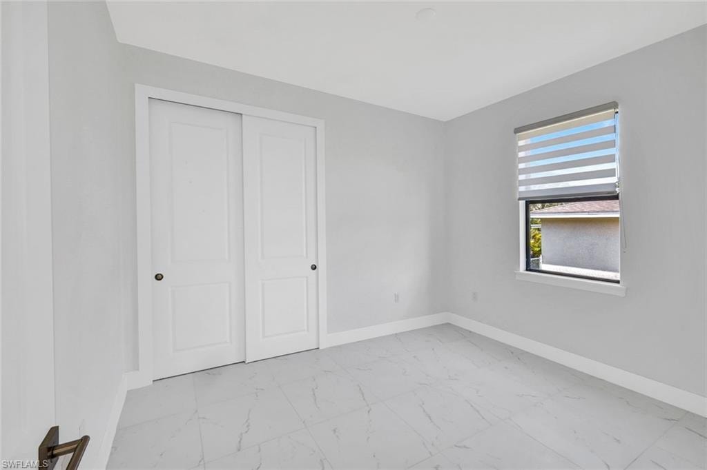 Unfurnished bedroom with light marble finish flooring and a closet