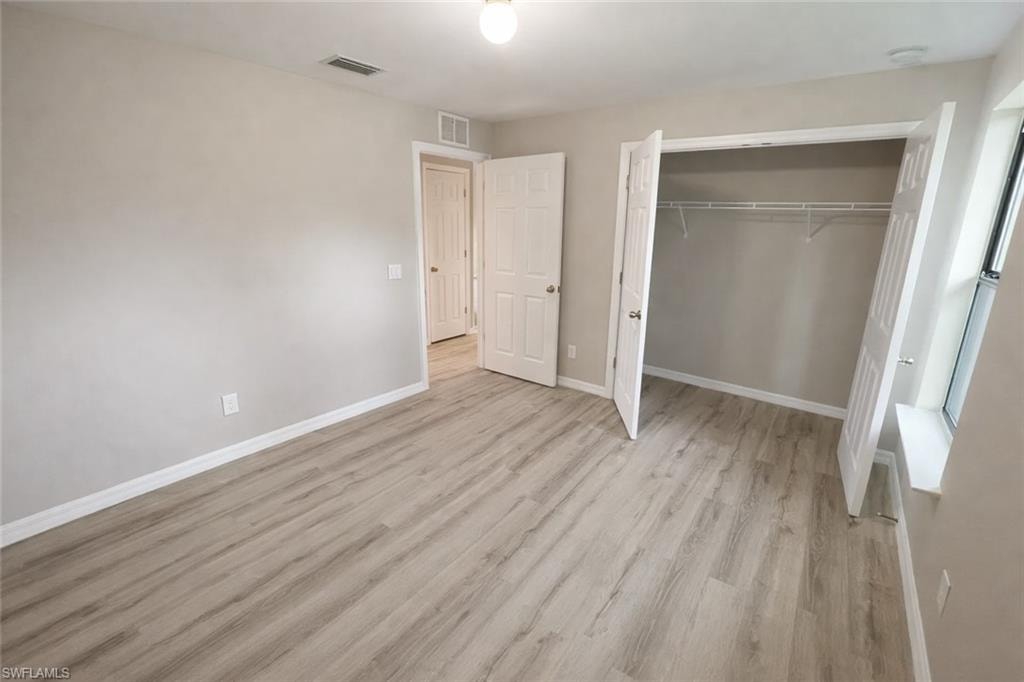 Unfurnished bedroom featuring light wood-style floors and a closet