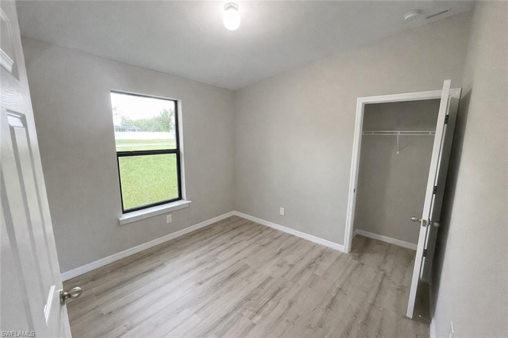 Unfurnished bedroom featuring light wood-type flooring and a spacious closet