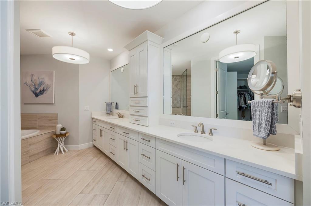 Full bath featuring double vanity, a walk in closet, a garden tub, and a stall shower