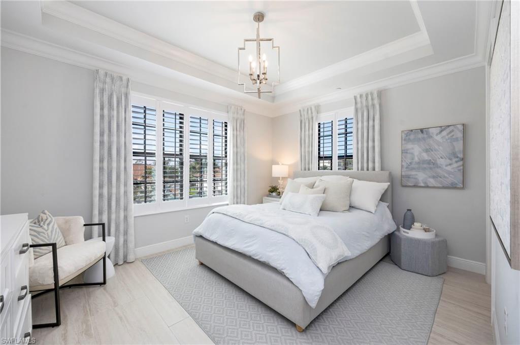 Bedroom with suspended lighting, a raised ceiling, and light wood-style flooring