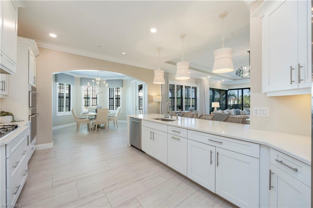 Kitchen with white cabinets, a peninsula, crown molding, hanging lights, and light stone countertops