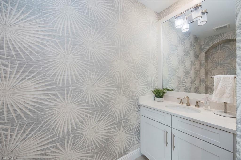 Bathroom with wallpapered walls and vanity