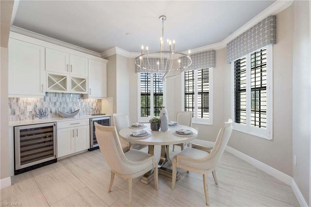 Dining room with beverage cooler, ornamental molding, suspended lighting, and a dry bar