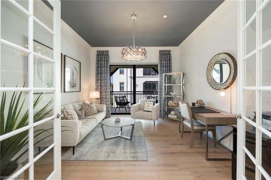 Living area with crown molding, light wood-style floors, a chandelier, and french doors