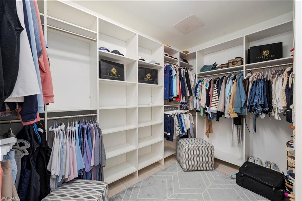 Walk in closet with attic access and light wood-style flooring
