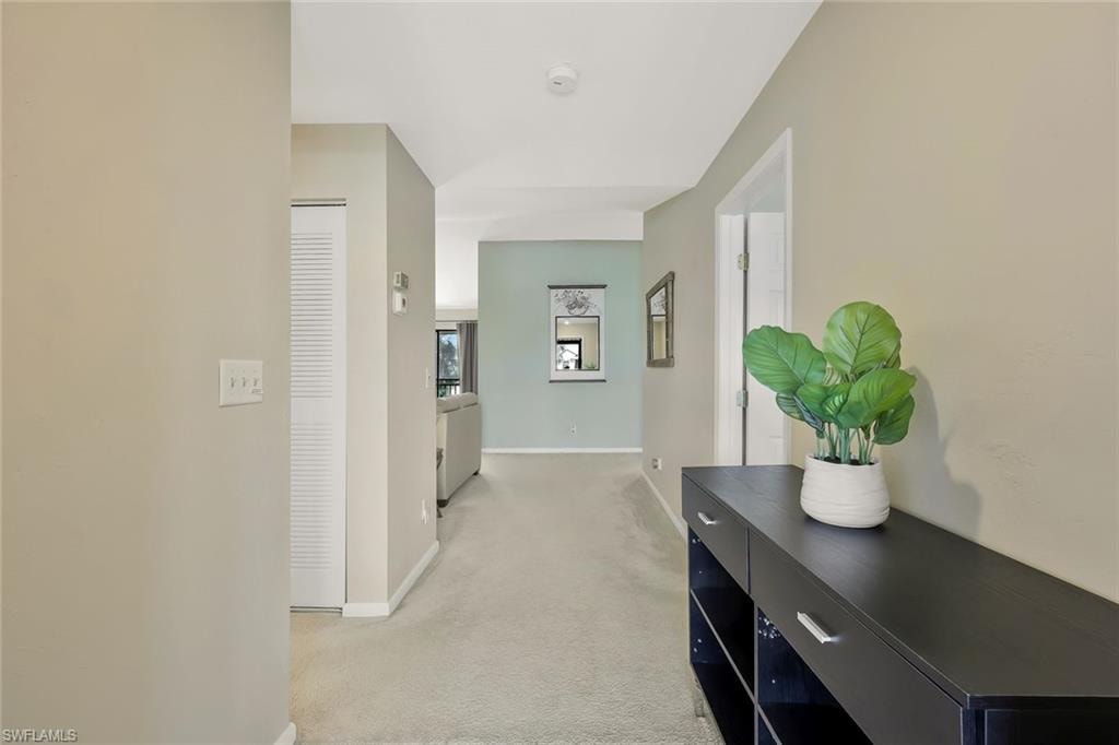 Corridor featuring light carpet and baseboards