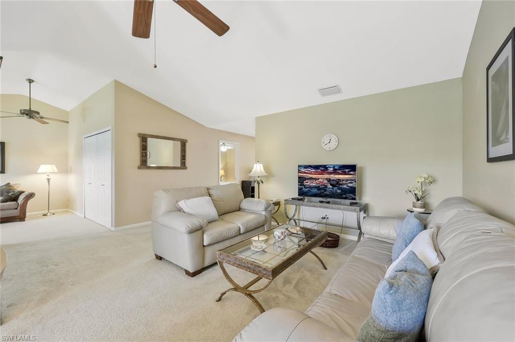 Living room with a ceiling fan, lofted ceiling, and carpet flooring