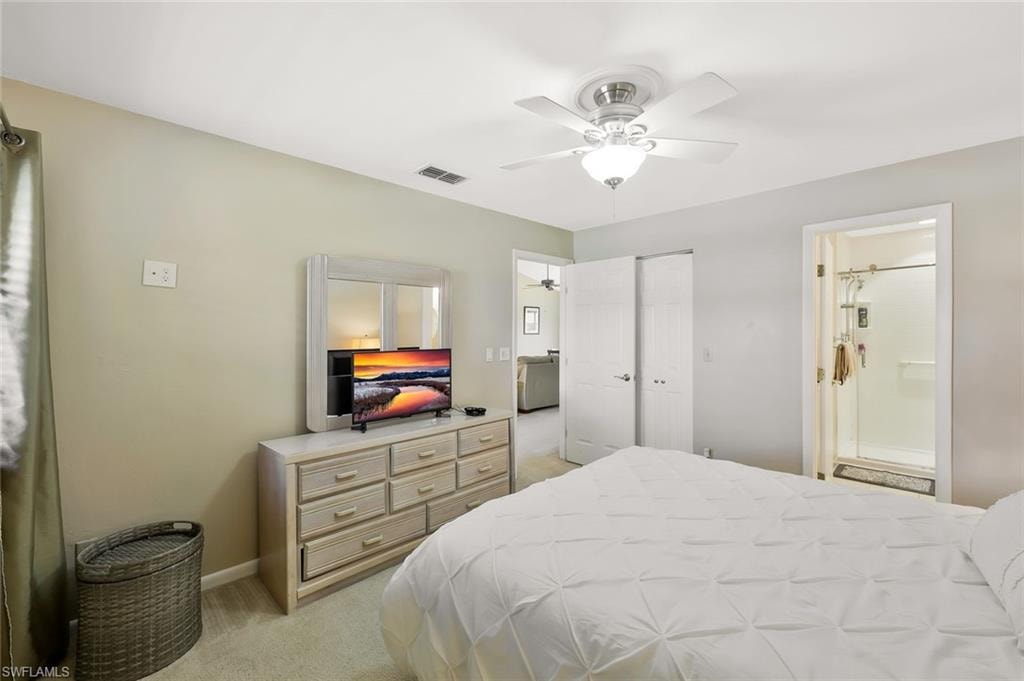 Bedroom with light carpet, a ceiling fan, a closet, and connected bathroom