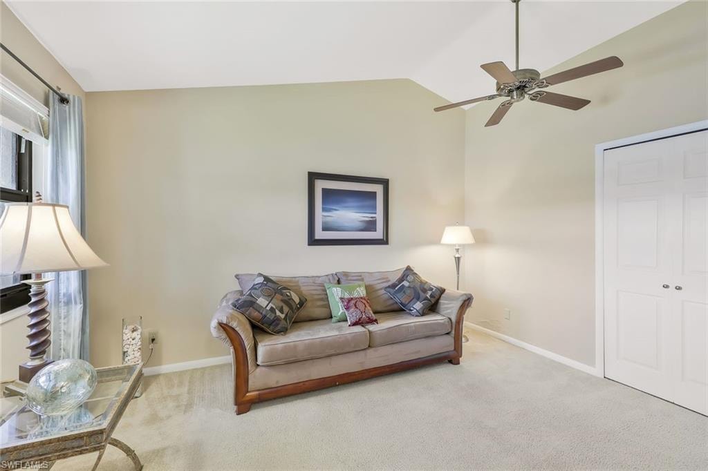 Living area featuring lofted ceiling, carpet flooring, and a ceiling fan