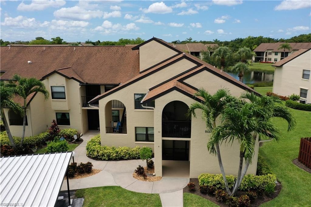 View of front of property with stucco siding, a front lawn, and a water view