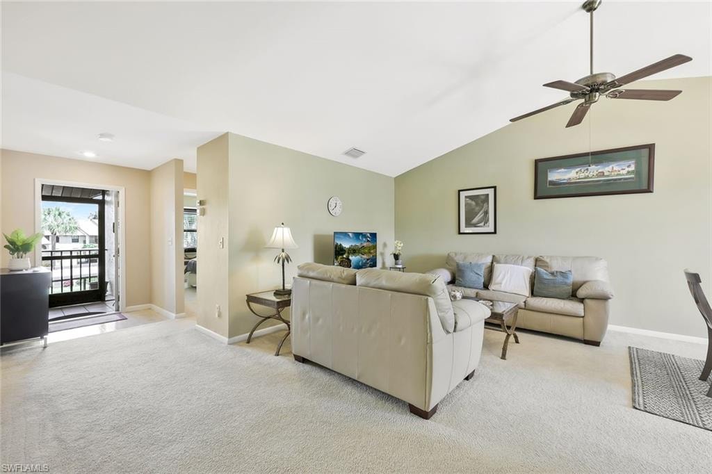 Living area featuring light carpet, a ceiling fan, and vaulted ceiling