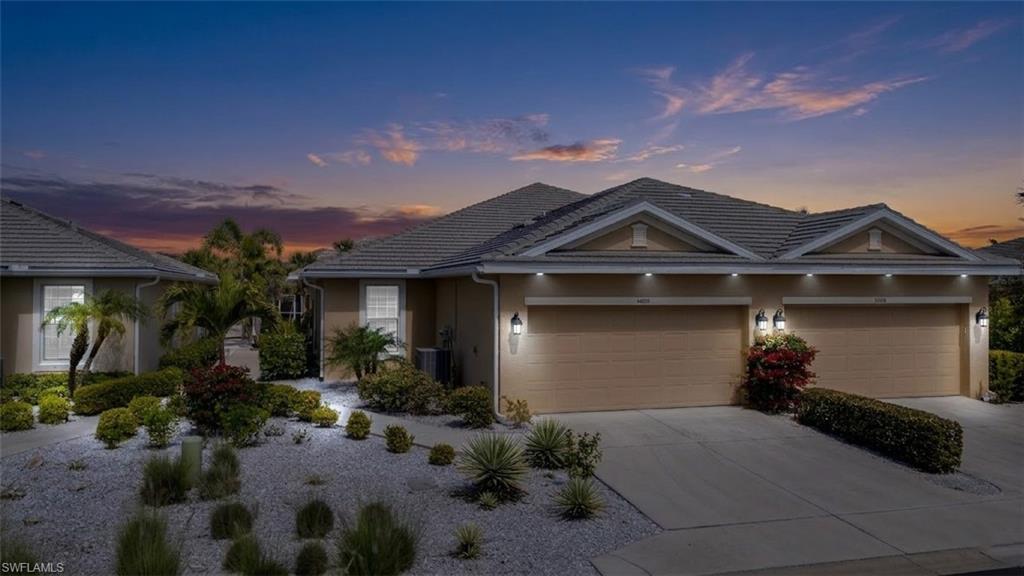 Ranch-style home featuring driveway, stucco siding, a garage, and a tiled roof