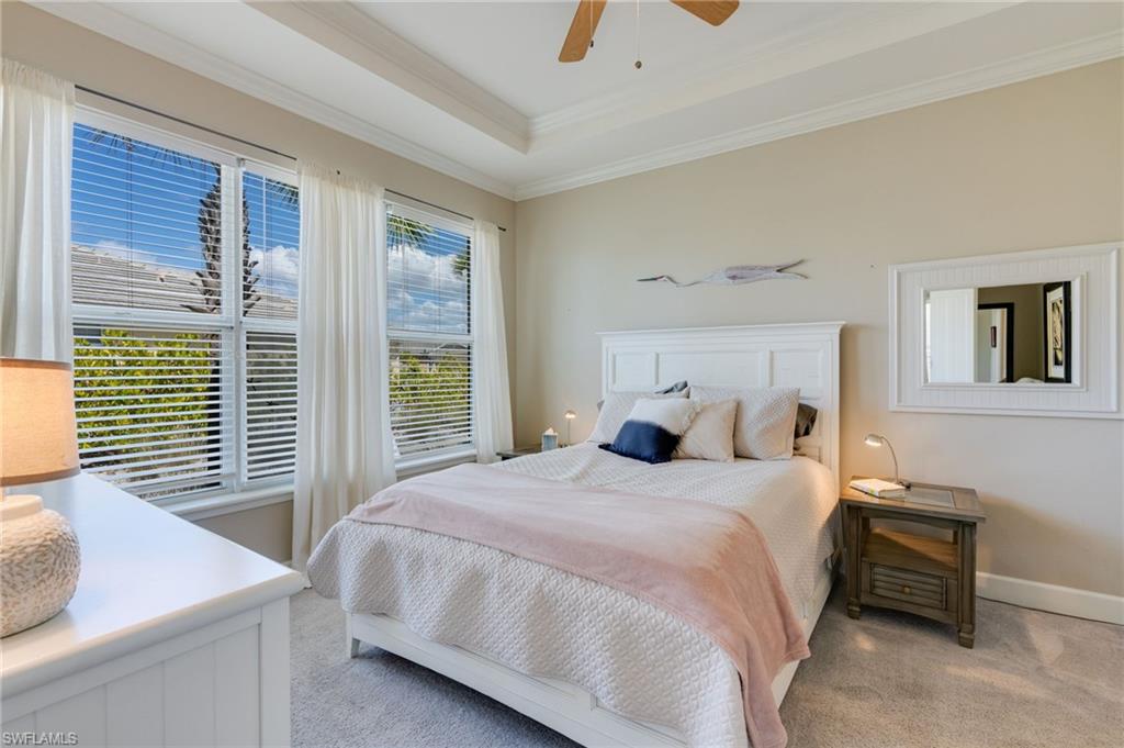 Bedroom featuring light carpet, crown molding, a tray ceiling, and ceiling fan