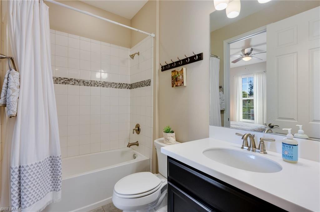 Full bathroom featuring vanity, shower / bathtub combination with curtain, and a ceiling fan