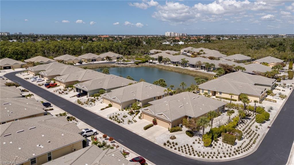 Aerial perspective of suburban area featuring a nearby body of water and a tree filled landscape