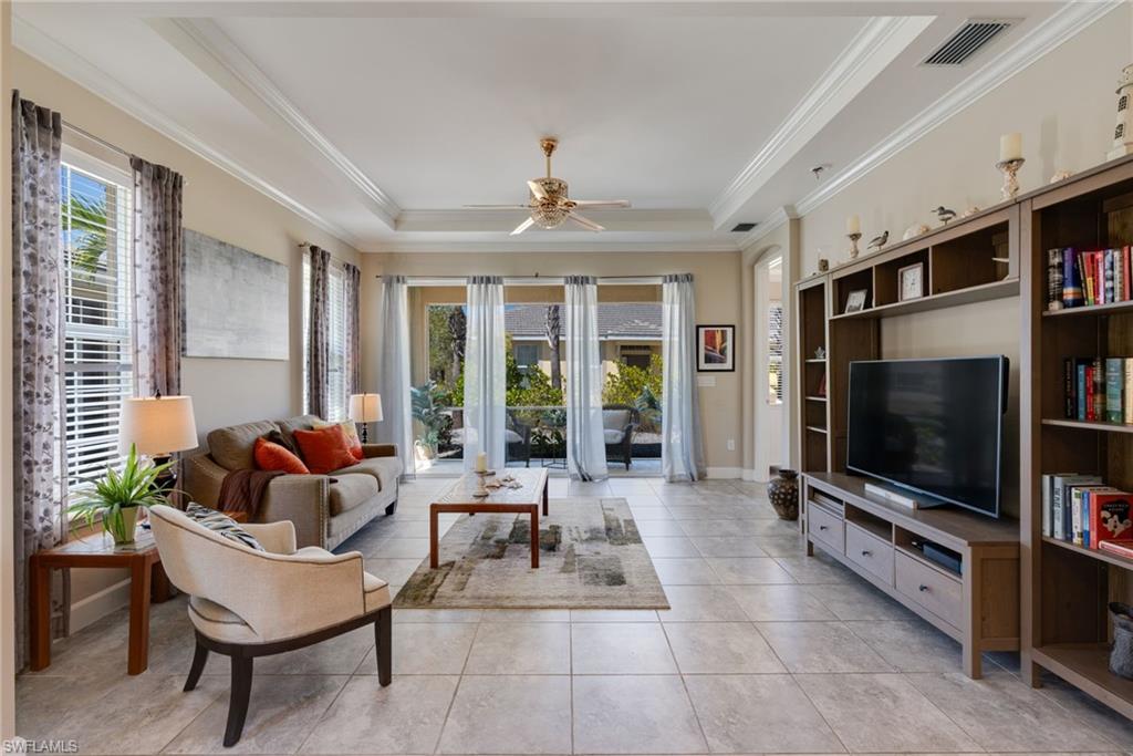 Living area featuring a ceiling fan, a tray ceiling, and crown molding
