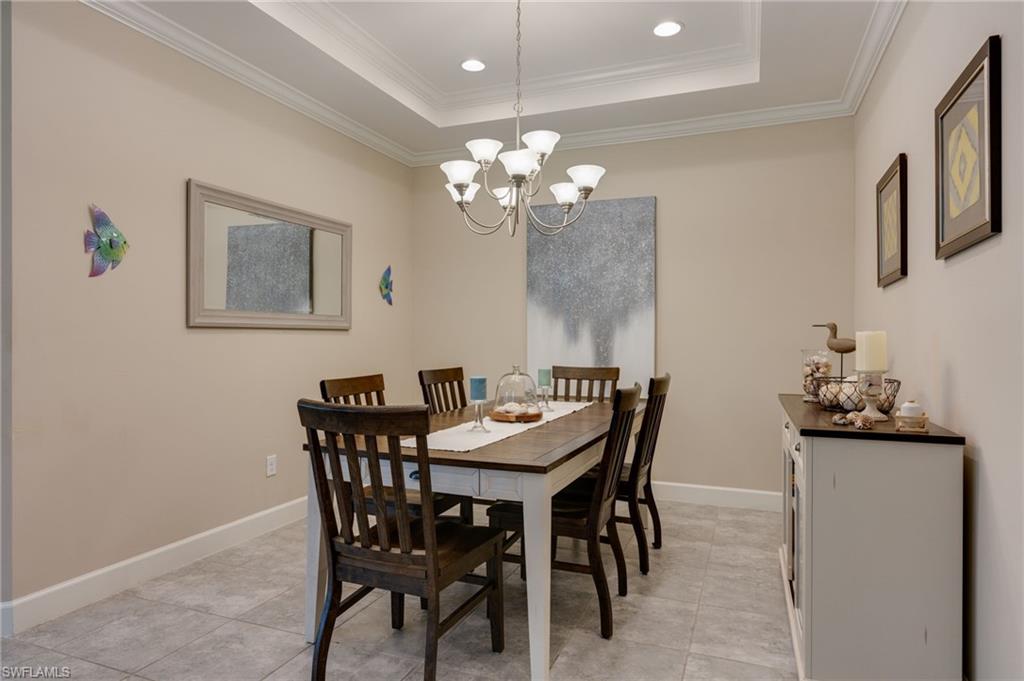 Dining area with crown molding, suspended lighting, a raised ceiling, and light tile patterned flooring