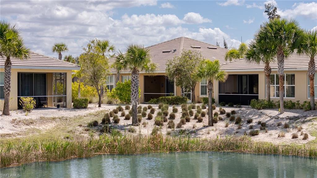 Rear view of house featuring a sunroom, a tiled roof, stucco siding, and a water view