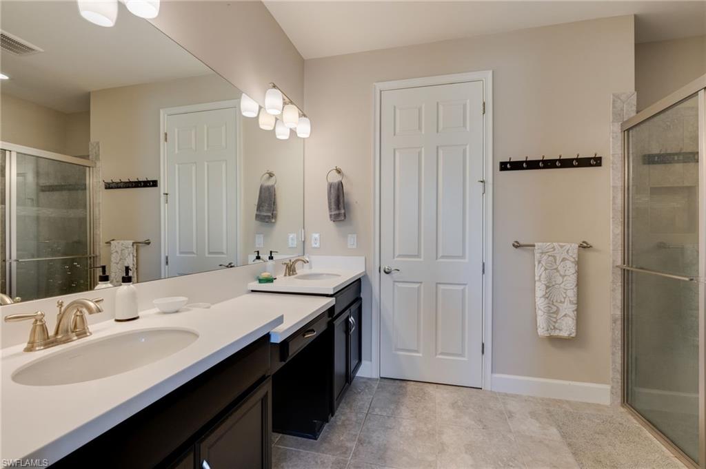Full bath with a stall shower, double vanity, and light tile patterned floors