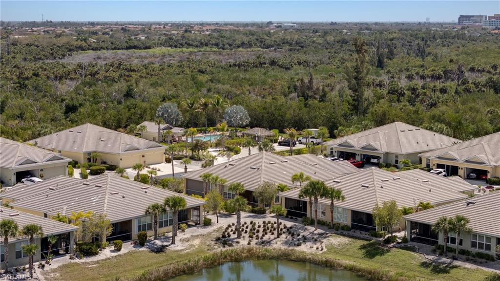 Aerial perspective of suburban area featuring a heavily wooded area and a nearby body of water