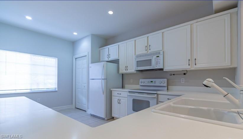 Kitchen featuring white appliances, recessed lighting, a sink, light countertops, and white cabinets