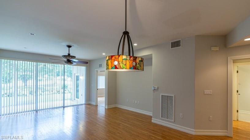 Unfurnished room with visible vents, ceiling fan, baseboards, and wood finished floors