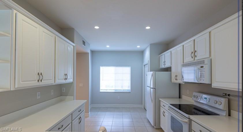 Kitchen with recessed lighting, white cabinets, white appliances, and light countertops