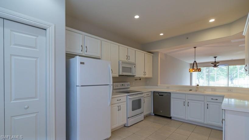 Kitchen with white appliances, recessed lighting, light countertops, pendant lighting, and white cabinetry