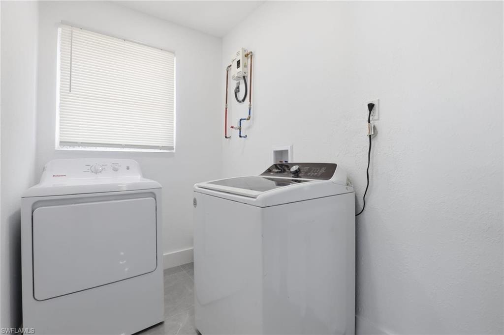 Laundry area with washing machine and dryer and light tile patterned floors