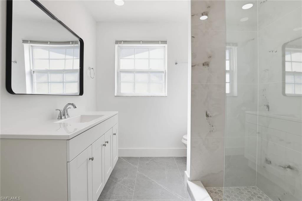 Full bath with vanity, tiled shower, light tile patterned floors, and recessed lighting