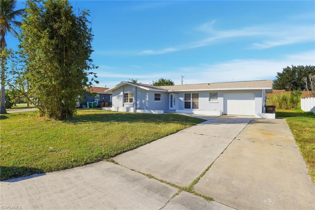 Ranch-style home with driveway, a front lawn, stucco siding, and an attached garage