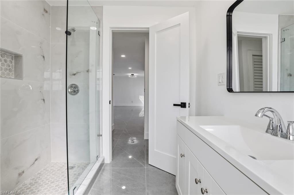 Bathroom featuring vanity, a stall shower, light tile patterned floors, and recessed lighting