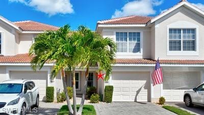 View of front of home featuring a tile roof, an attached garage, driveway, and stucco siding