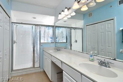 Full bathroom with a closet, double vanity, and a stall shower